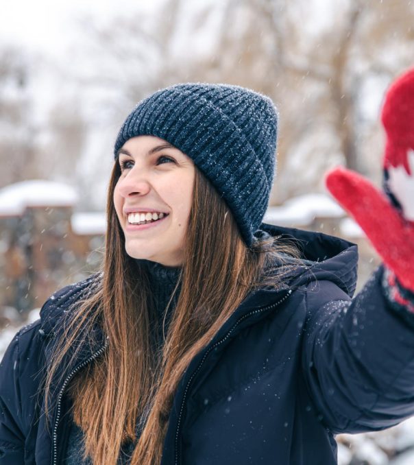 happy-young-woman-in-red-mittens-with-the-flag-of-canada-in-snowy-weather